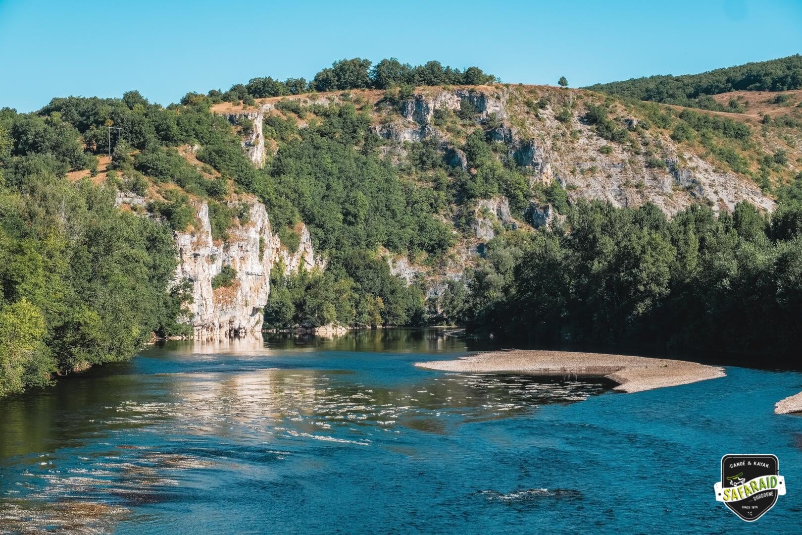 Plage de galet au milieu de la rivière à côté d'une falaise.