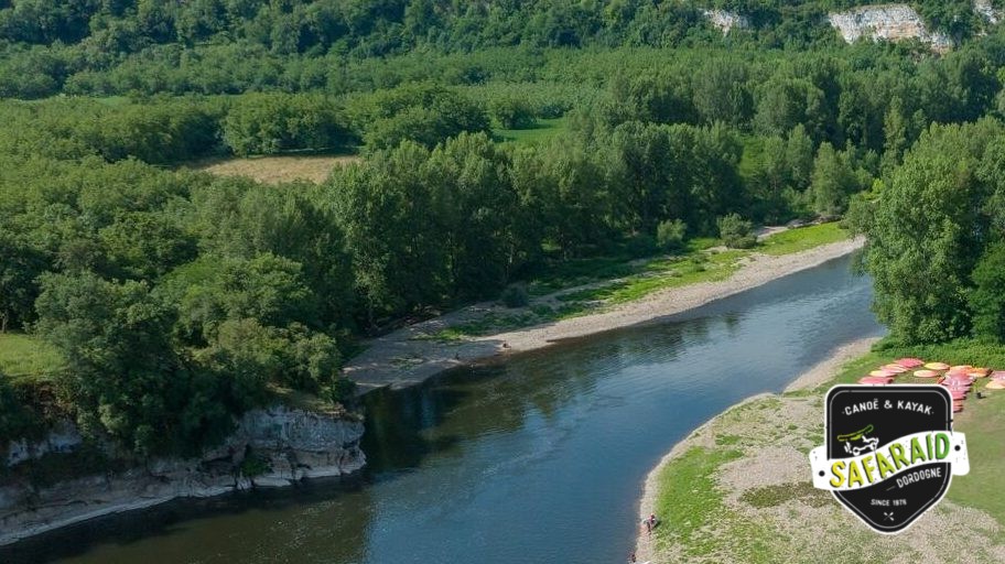 Rivière avec une petite plage de galet à côté d'une petit grotte, juste à coté des falaises.